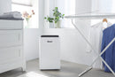 White dehumidifier in a room with a drying rack and laundry items.