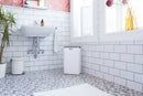 Bathroom with white tiled walls, a sink, and a small refrigerator.